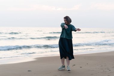 Kız deniz kıyısında kazakla dans ediyor.