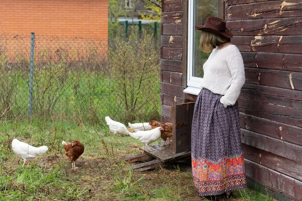 a village girl stands in a village near chickens