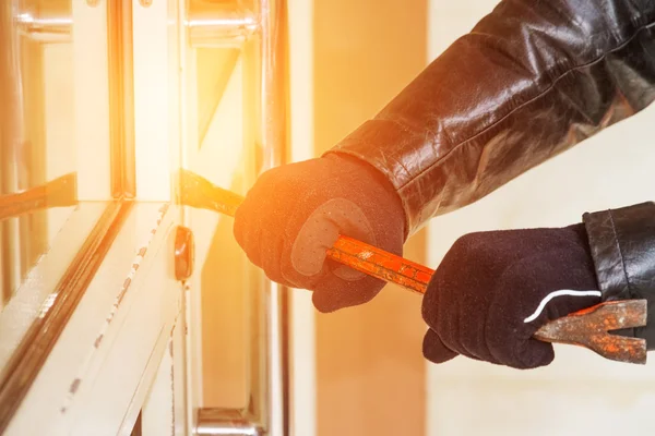 Burglar wearing leather coat breaking in a house — Stock Photo, Image