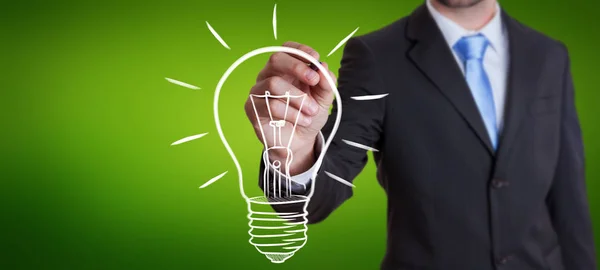 Businessman drawing a sketch lightbulb with a pen — Stock Photo, Image