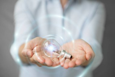 Bağlantıları olan bir lighbulb elinde tutan işkadını