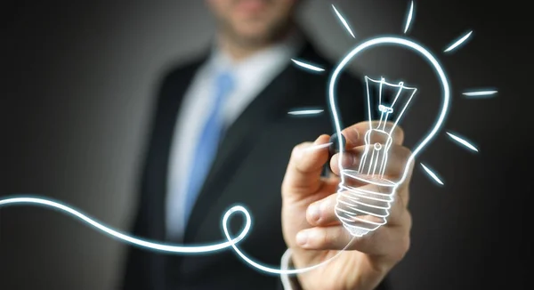 Businessman drawing a sketch lightbulb with a pen — Stock Photo, Image