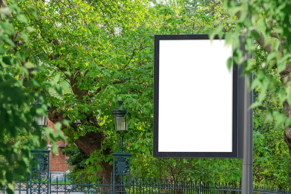 Billboard Mockup in a city with natural landscape. Parisian style hoarding advertisement on a pole close to a park with green trees