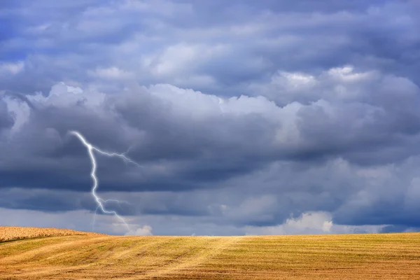 Dark storm clouds and lightning above autumn fields after harvesting — Stock Photo, Image