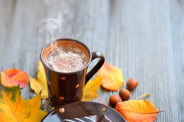 秋の紅葉と木製の表面の背景にコーヒー カップ — ストック写真