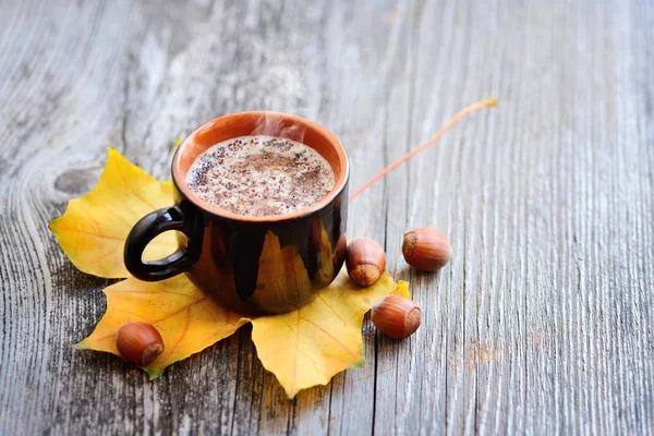 Xícara de café no outono folhas de outono e fundo de superfície de madeira — Fotografia de Stock