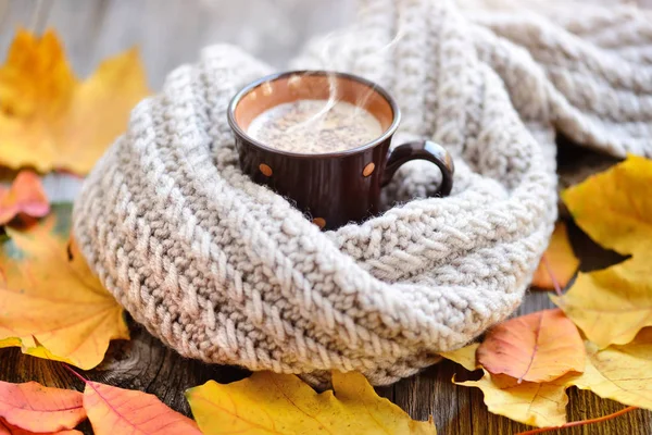 Herbstblätter, heiße Tasse Kaffee und ein warmer Schal auf hölzernem Tischhintergrund. Morgenkaffee, Sonntagsruhe und Stilllebenskonzept. — Stockfoto