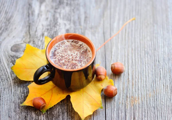 Taza de café en las hojas de otoño y fondo de superficie de madera — Foto de Stock