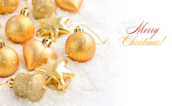 Christmas gold ornaments on the snow. Festive Christmas background — Stock Photo, Image