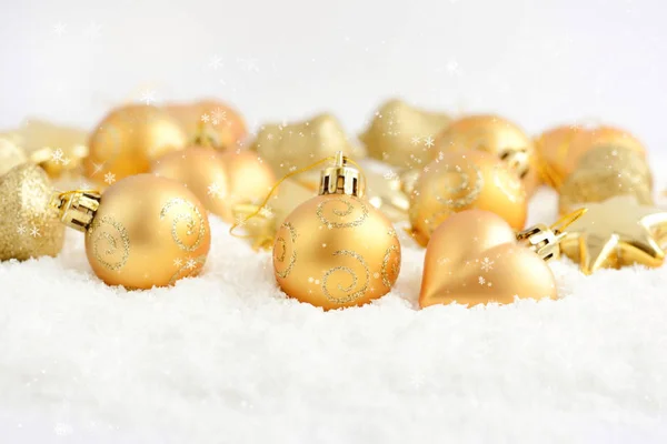 Christmas gold ornaments on the snow. Festive Christmas background