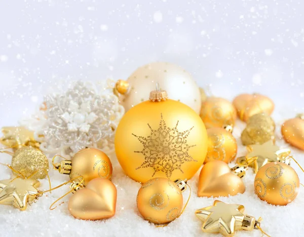 Christmas gold ornaments on the snow. Festive Christmas background