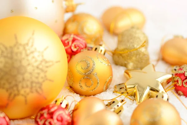 Χριστούγεννα χρυσά και κόκκινα στολίδια πάνω στο χιόνι. Εορταστικό χριστουγεννιάτικο φόντο — Φωτογραφία Αρχείου