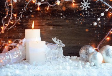 Bir geyik ile kar ve Noel ışıkları Noel dekoratif topları ile iki yanan mumlar. Noel dekorasyonları ahşap arka plan üzerinde. Neşeli Noel arka plan