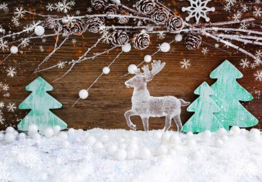 Noel kartı ahşap Noel ağaçları ve ahşap arka plan üzerinde kar üzerinde bir geyik. Neşeli Noel arka plan
