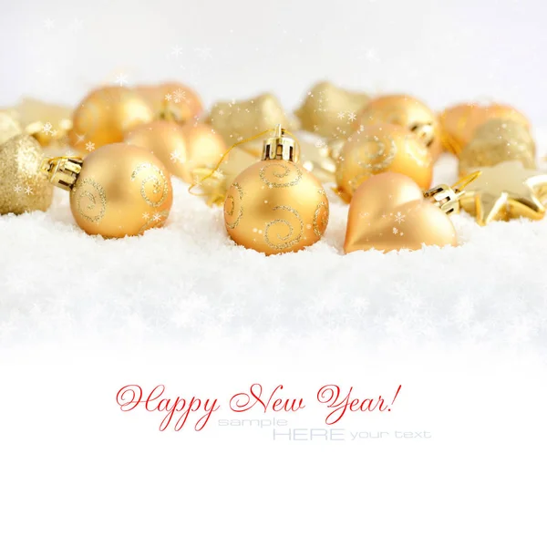 Christmas gold ornaments on the snow. Festive Christmas background — Stock Photo, Image