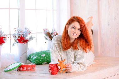 Yerde yatarken ve gülümseyen güzel kızıl saçlı kadın. Noel kavramı. Noel güneşli sabah