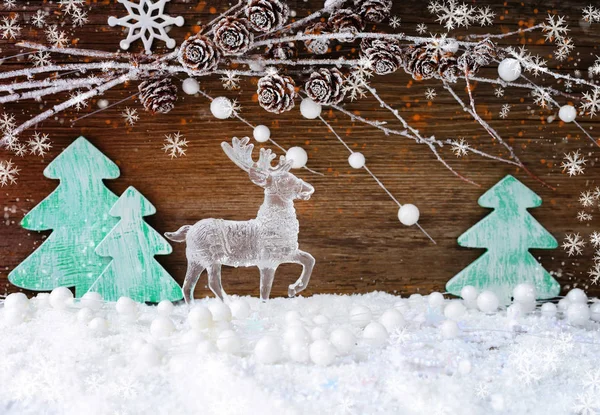 Tarjeta de Navidad con árboles de Navidad de madera y un ciervo en la nieve sobre un fondo de madera. Fondo navideño festivo —  Fotos de Stock