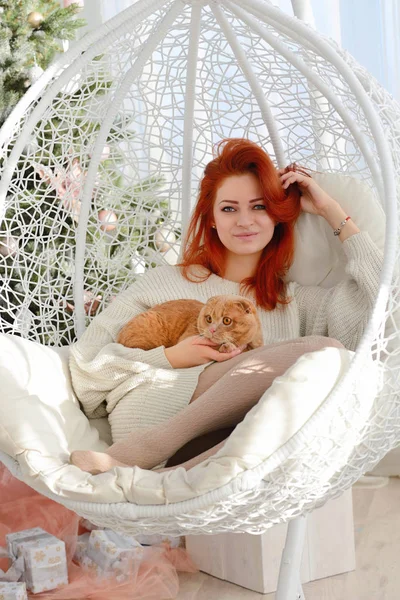 Mooie jonge vrouw met rode kat. Het concept van Kerstmis. Zonnige kerstochtend. — Stockfoto