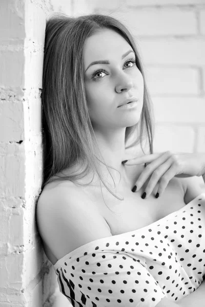 Black and white portrait of a beautiful female. Attractive young woman leaned on a white brick wall — Stock Photo, Image