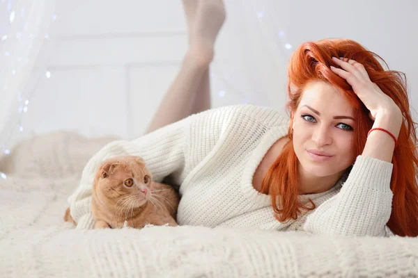 Mooie jonge vrouw met rode kat. Het concept van Kerstmis. Zonnige kerstochtend. — Stockfoto