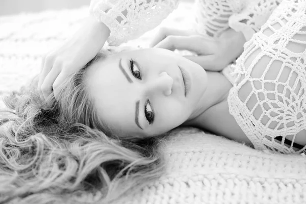 Hübsche Frau, die sich zu Hause auf ihr Bett legt. verführerisches Mädchen in Weiß. — Stockfoto