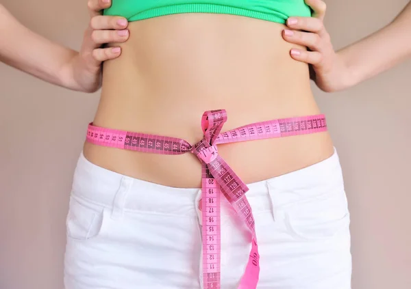 Woman measuring waist with tape on knot, dieting concept. — Stock Photo, Image