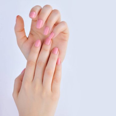 Elinde çivi beyaz arka plan üzerinde pembe manikür genç bir kadınla closeup