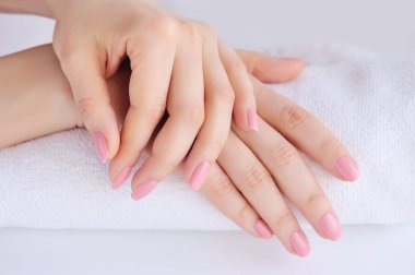 Ellerin bir kadının pembe manikür ile bir havlu üzerinde