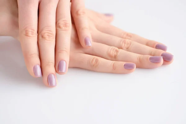 Gros plan des mains d'une jeune femme avec manucure rose sur les ongles sur fond blanc — Photo