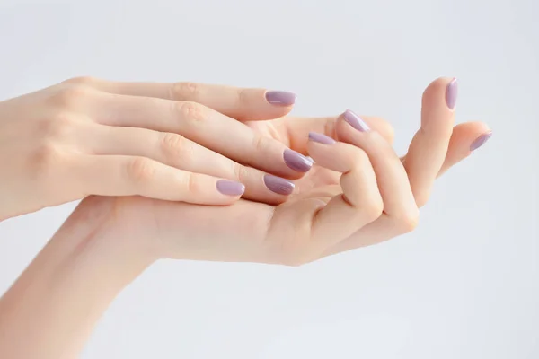 Close-up de mãos de uma jovem mulher com manicure rosa em pregos contra fundo branco — Fotografia de Stock