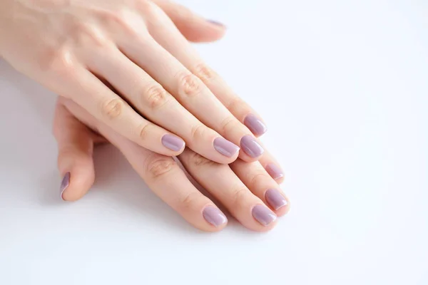 Gros plan des mains d'une jeune femme avec manucure rose sur les ongles sur fond blanc — Photo