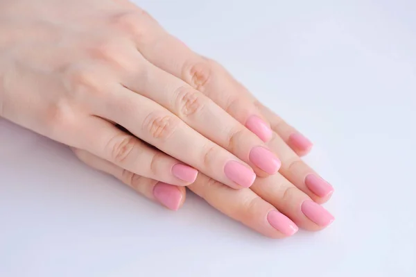 Gros plan des mains d'une jeune femme avec manucure rose sur les ongles sur fond blanc — Photo