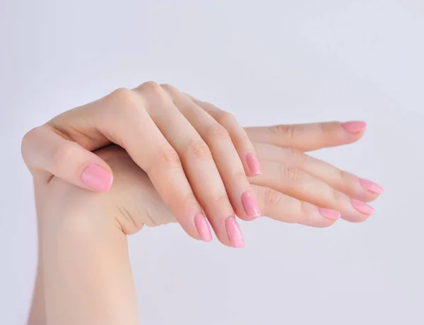 Gros plan des mains d'une jeune femme avec manucure rose sur les ongles sur fond blanc — Photo