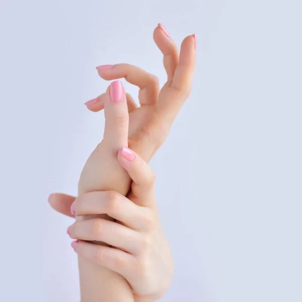 Nahaufnahme der Hände einer jungen Frau mit rosa Maniküre auf Nägeln vor weißem Hintergrund — Stockfoto