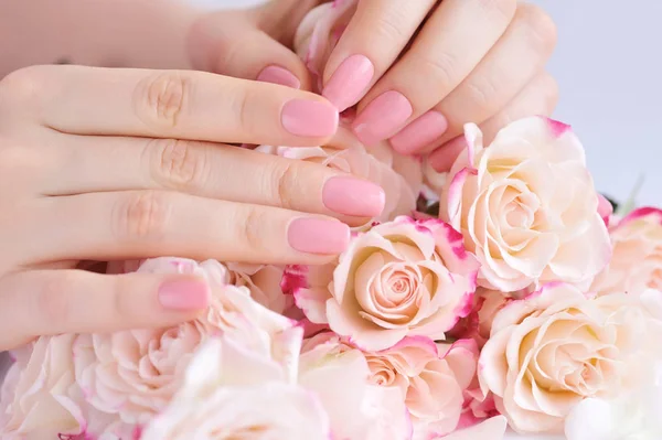 Hände einer Frau mit rosa Maniküre auf Nägeln und Rosen — Stockfoto