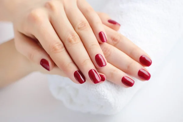 As mãos de uma mulher com manicura vermelha estão em uma toalha — Fotografia de Stock