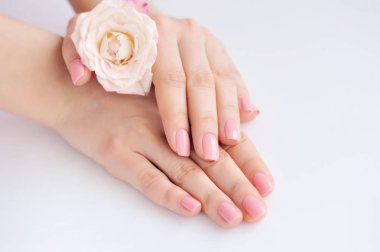 Elinde çivi ve gül pembe manikür olan bir kadın