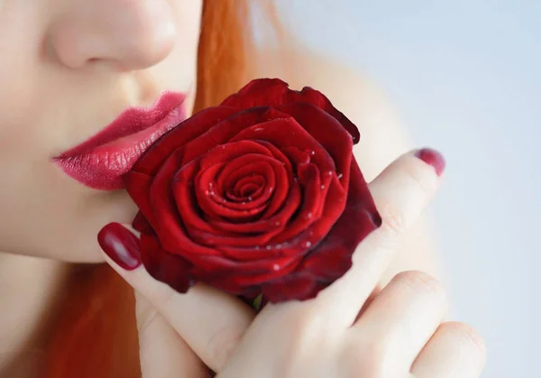 Portrait avec fleur de rose rouge. Lèvres et ongles rouge foncé. Belle jeune femme rousse . — Photo