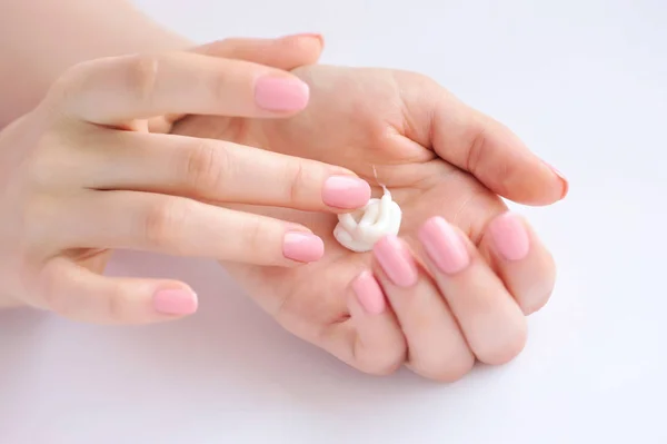 Young woman with pink manicure applies cream on her hands — Stock Photo, Image