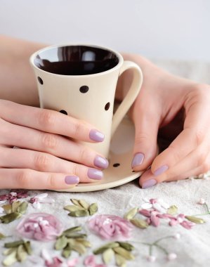 Kız kahve fincan keten masa örtüsü üzerinde eller