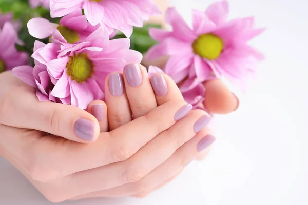 Pembe manikür çivi ve pembe çiçekler ile bir kadının elleri — Stok fotoğraf