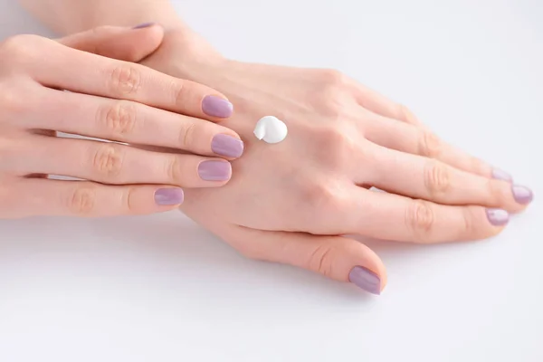 Young woman with pink manicure applies cream on her hands — Stock Photo, Image