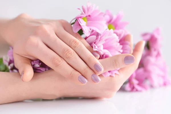 Handen van een vrouw met roze manicure nagels en roze bloemen — Stockfoto