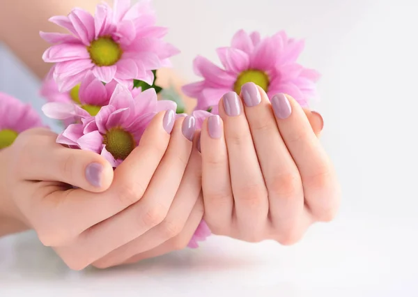 Hände einer Frau mit rosa Maniküre auf Nägeln und rosa Blumen — Stockfoto