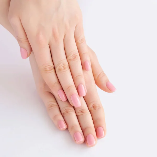 Крупный план рук молодой женщины с розовым маникюром на ногтях — стоковое фото