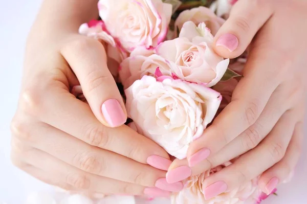 Mãos de uma mulher com manicure rosa em pregos e rosas — Fotografia de Stock