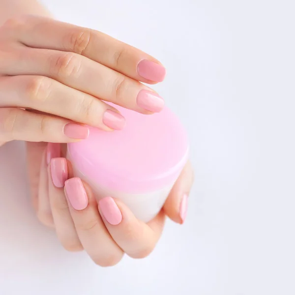 Τα χέρια του μια γυναίκα με ροζ μανικιούρ με κρέμα — Φωτογραφία Αρχείου