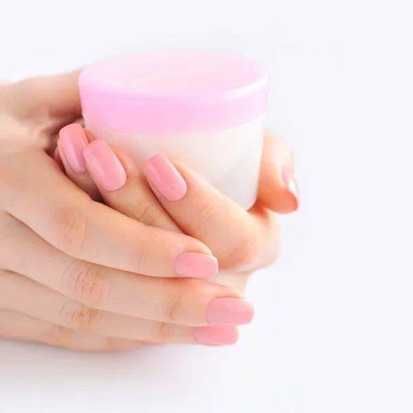 Mãos de uma mulher com manicure rosa com creme — Fotografia de Stock