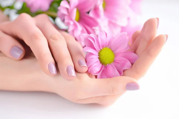 Hände einer Frau mit rosa Maniküre auf Nägeln und rosa Blumen — Stockfoto