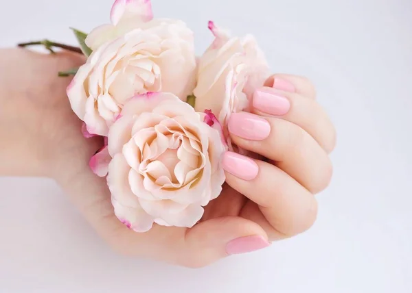 Handen van een vrouw met roze manicure nagels en rozen — Stockfoto